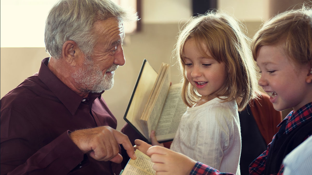Grandfather showing Grandkids something in the Bible and they are all smiling
