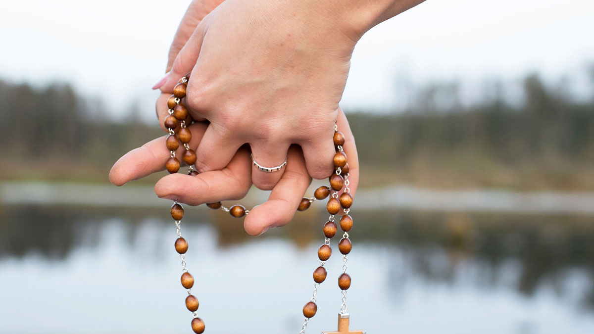 Married couple holding hands with a rosary entwined in their hands
