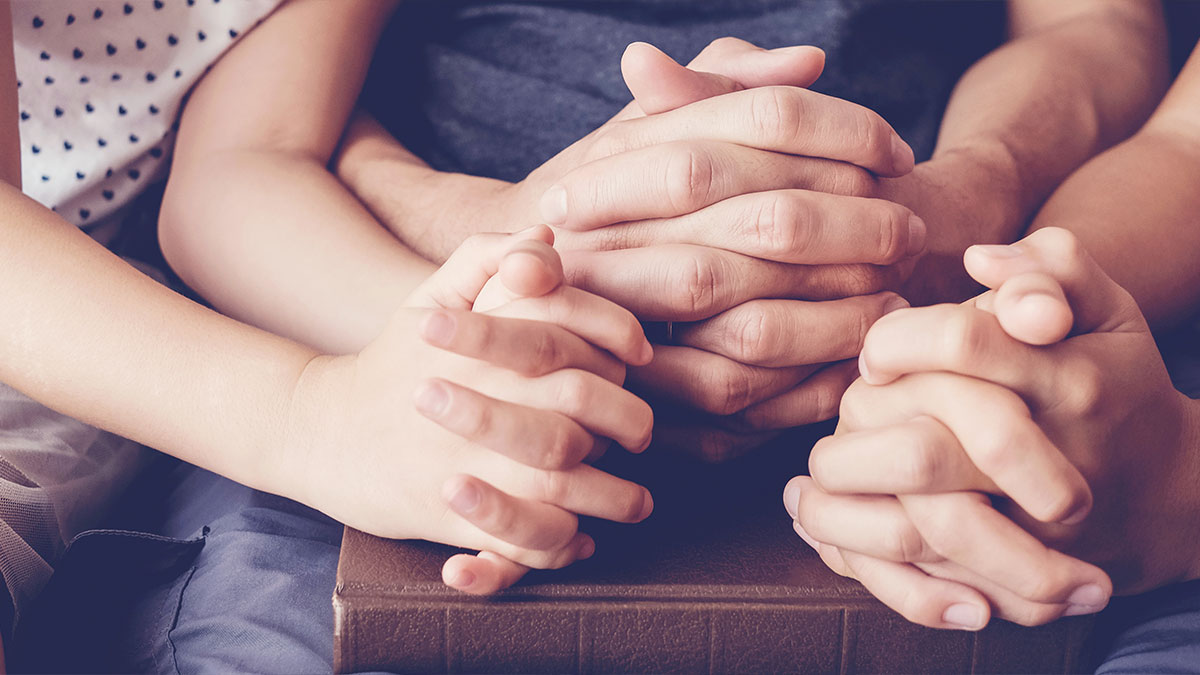 Parent and children folded hands in prayer together