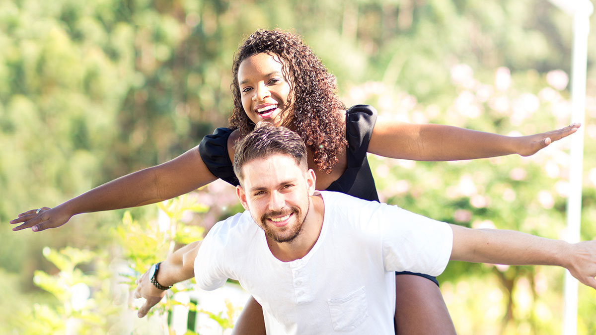 Couple with their arms out as though flying and smiling/laughing as though they are having a lot of fun.